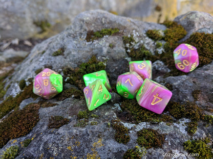 Marbled pearly green and pink Tulip dice set on mossy rock for tabletop role-playing games.