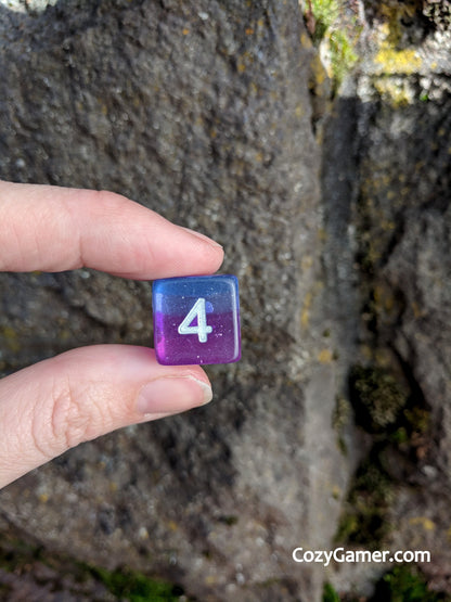 Hand holding a translucent purple and blue die with silver glitter, showcasing the number four, from the Twilight DnD Dice Set.