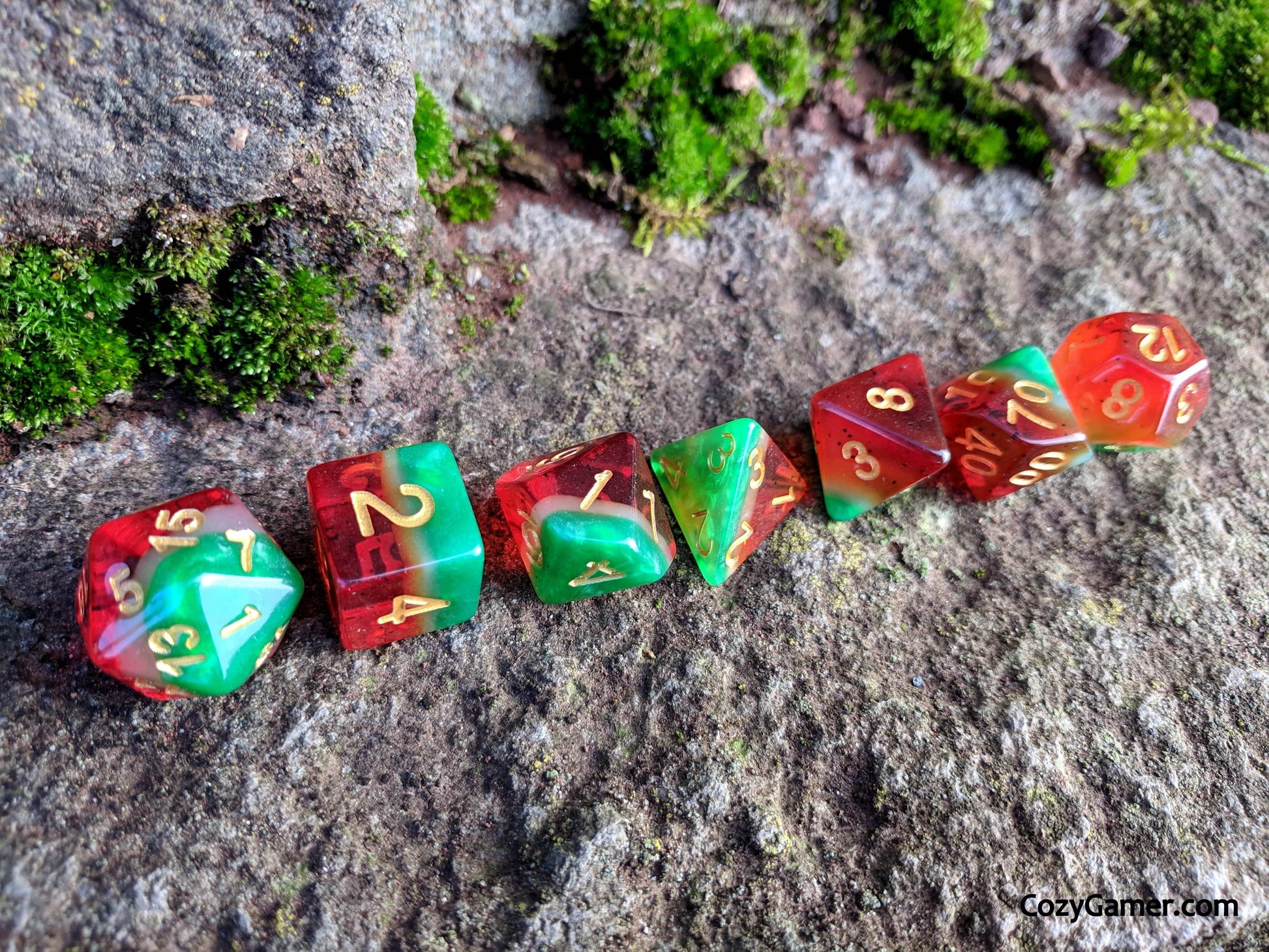 Watermelon DnD Dice Set with red, white, and green transparent colors displayed on a mossy rock surface.