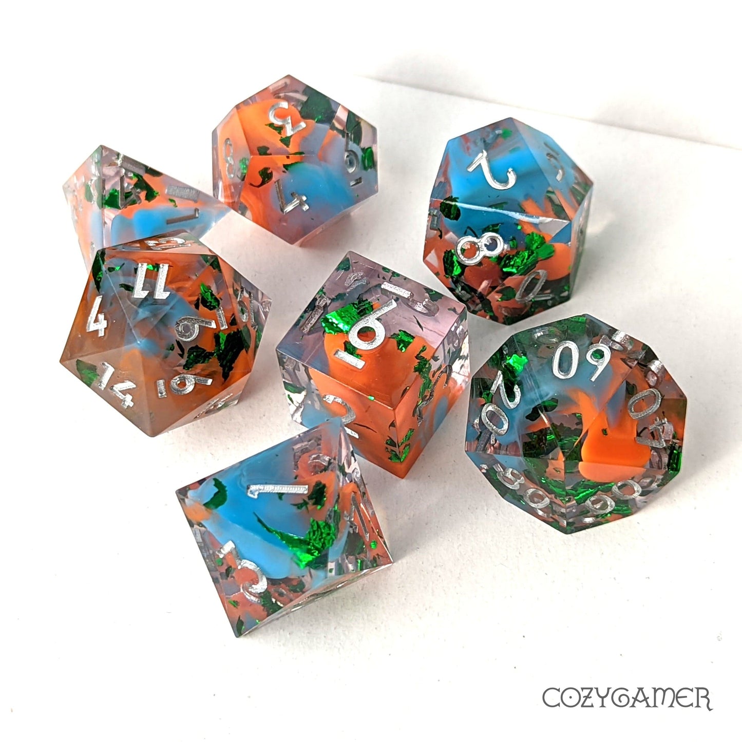 7-piece Wizard Robes sharp edge resin dice set with blue, orange swirls and green foil, perfect for DND and TTRPG players.